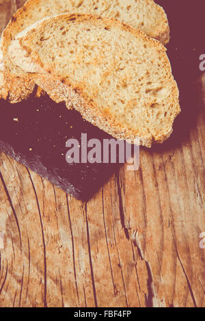 Some sliced bread during the preparation of the typical italian's starter: 'Bruschetta'. Toned image Stock Photo