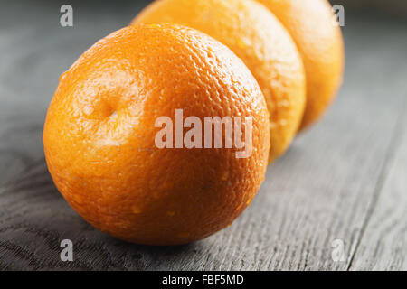three ripe oranges on wooden table Stock Photo