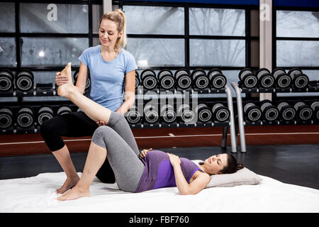 Pregnant woman doing some exercising helped by trainer Stock Photo