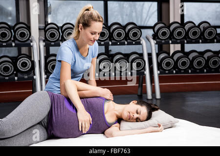 Pregnant woman doing some exercising helped by trainer Stock Photo