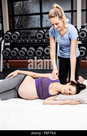 Pregnant woman doing some exercising helped by trainer Stock Photo