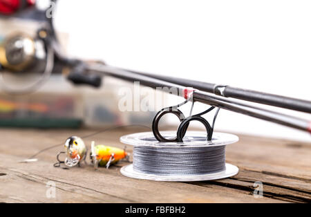 closeup guide rings on graphite rods and watted cord with blur background from fishing tackles and lure boxes. Stock Photo