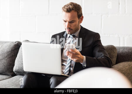 Focused businessman using laptop and smartphone Stock Photo
