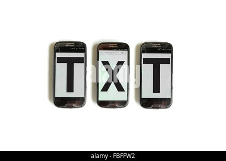 TXT written on the screens of smartphones photographed against a white background. Stock Photo