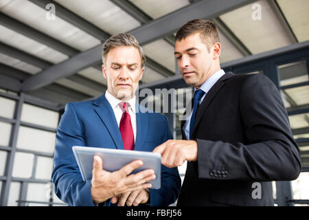 Businessmen talking together while looking tablet Stock Photo