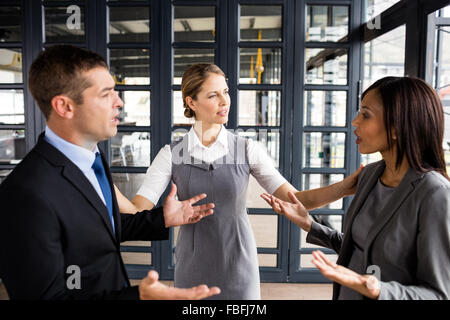 Business people arguing together while businesswoman putting hands up Stock Photo
