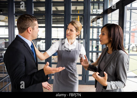 Business people arguing together while businesswoman putting hands up Stock Photo