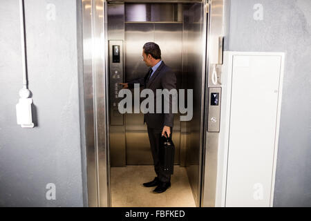 Smiling businessman pressing elevators button Stock Photo