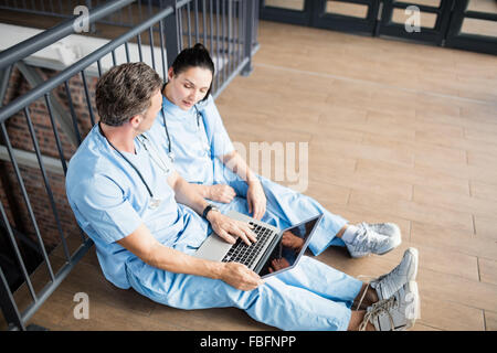 Doctors using laptop while sitting on floor Stock Photo