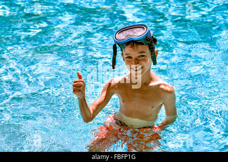 Boy kid child eight years old inside swimming pool portrait happy fun bright day diving goggles thumbs up