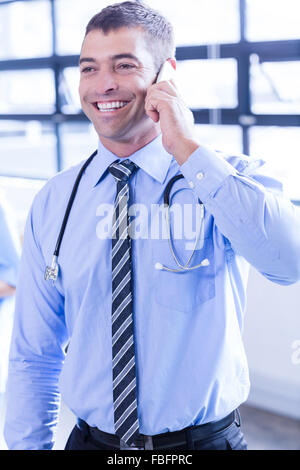 Smiling male doctor using smartphone Stock Photo