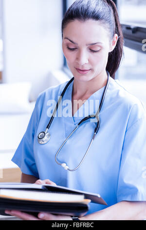 Serious nurse holding report on clipboard Stock Photo