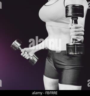 Composite image of close-up of dumbbells by slim woman Stock Photo