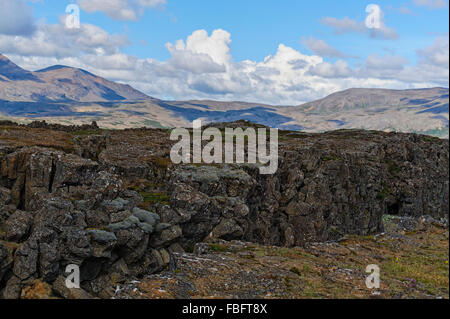 Beautiful Icelandic landscape with volcanic rock outcropping, mountains, blue sky and cumulus clouds in Iceland, Europe