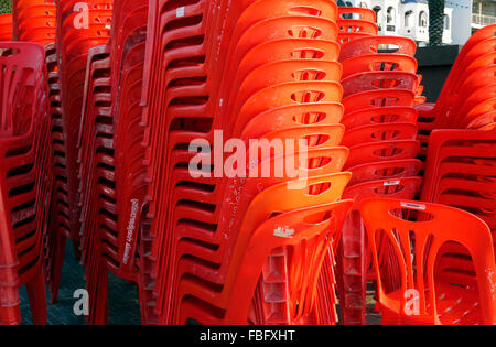 A large number of red plastic stacking chairs Stock Photo