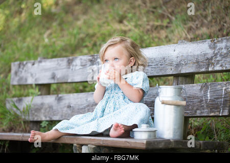 Girl drinking milk on a bench at an Alpine hut, Germany Stock Photo