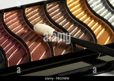 Close up view of compact makeup case with applicator on top of various eye shadow colors Stock Photo