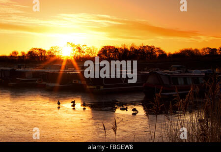 Sunrise over St. Mary's Marina, Rufford, Lancashire, UK. 16th Jan 2016. UK Weather forecast continues to be cold with ice and frost.  A beautiful sunrise elevates above the rolling pennine hills, silhouetting the resting canal boats on Rufford Marina in Lancashire. [Image taken from public land] Credit:  Cernan Elias/Alamy Live News Stock Photo