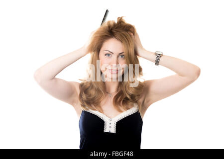 Funny portrait of young attractive cheerful smiling blond woman with long hair holding comb, looking at camera as in mirror, try Stock Photo