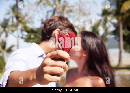 Happy couple kissing behind a red heart isolated on white background ...