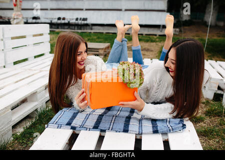 Girls lie on the bench and give each other gifts Stock Photo