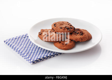 Pile of homemade chocolate chip cookies on white ceramic plate on blue napkin, isolated on white background Stock Photo