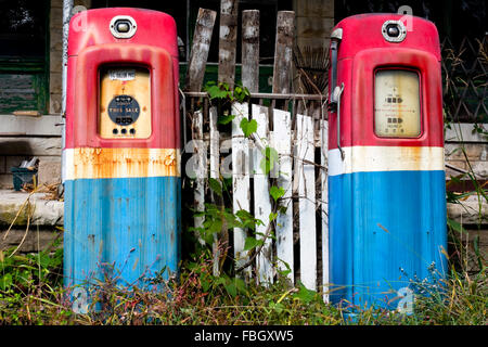 Old gas pumps sits resting in front of a closed general store and gas station. Stock Photo