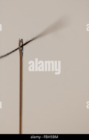A string being thread through the eye of a needle Stock Photo