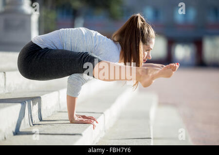 Yoga in the city: beautiful young fit woman wearing sportswear working out on the street on summer day, doing handstand, variati Stock Photo