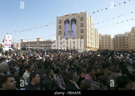 Khan Younis, Gaza Strip, Palestinian Territory. 16th Jan, 2016. Palestinians gather at the Qatari-funded Hamad City housing complex in Khan Younis, southern Gaza Strip, Saturday, Jan. 16, 2016. More than 1,000 Palestinian families have taken possession of new apartments in the first phase of the large housing project that sits on dunes that were part of the former Israeli Jewish settlement of Gush Katif. Huge portraits of former Qatari ruler, Sheik Hamad bin Khalifa Al Thani, right, his son, the current emir, Tamim bin Hamad bin Khalifa Al Thani, and the Qatari flag hang on one of the buildin Stock Photo