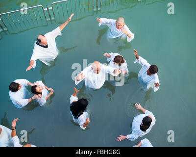 Christian group praying inside the water at the Yardenit baptismal site in Jordan river Stock Photo