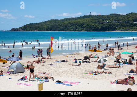 Main Beach at Byron Bay with sunbathers and Cape Byron Lighthouse in the distance,Australia. Stock Photo