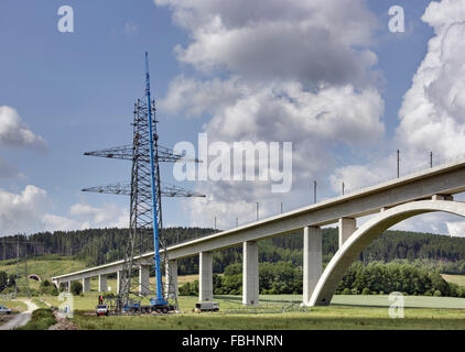 Power pole, bridge, men mounting high-voltage power pylon, crane, Thuringian Forest Stock Photo