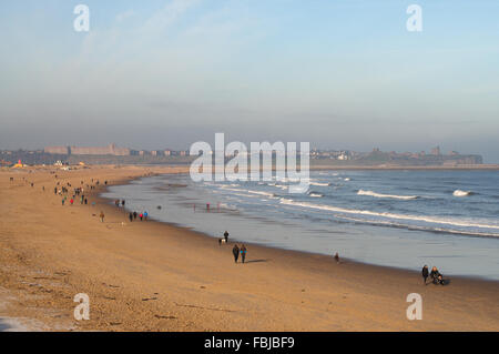 South Shields, UK. 17th January, 2016. Despite freezing temperatures walkers enjoy a glimpse of winter sunshine on Sandhaven beach in South Shields, South Tyneside. In the background Tynemouth is misty. Credit:  Washington Imaging/Alamy Live News Stock Photo