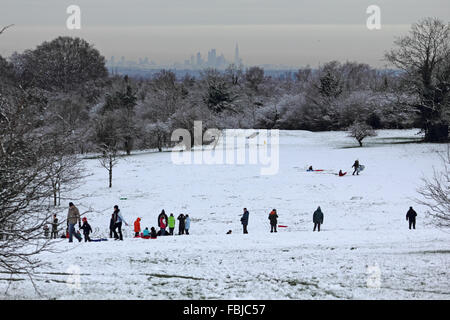 Epsom Downs, Surrey, UK. 17th January 2016. Overnight snowfall left a blanket of white across Epsom Downs which remained throughout the day. As part of the North Downs in Surrey, Epsom Downs is at a slightly higher elevation than the surrounding area and often has a covering when the nearby town is snow free. Families are out sledging with the city of London about 15 miles away, visible in the distance. Stock Photo