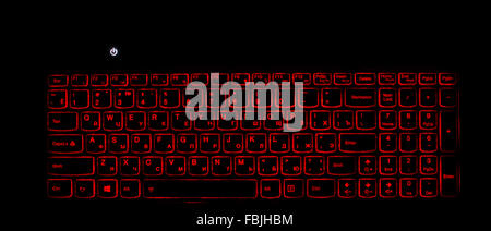 Laptop keyboard backlight. Red light and switched on computer. Dark background Stock Photo