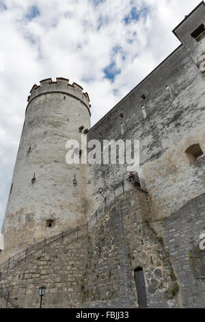 Middle aged tanned Caucasian woman stands on ancient walls and tower of fortress Hohensalzburg in Salzburg, Austria. Stock Photo