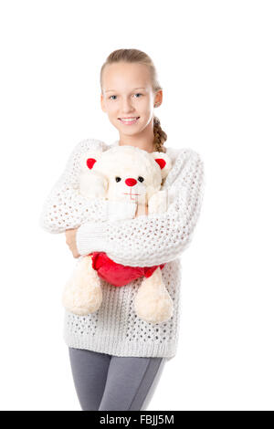 Portrait of happy beautiful casual caucasian teenage girl wearing knitted sweater hugging stuffed toy, friendly smiling Stock Photo