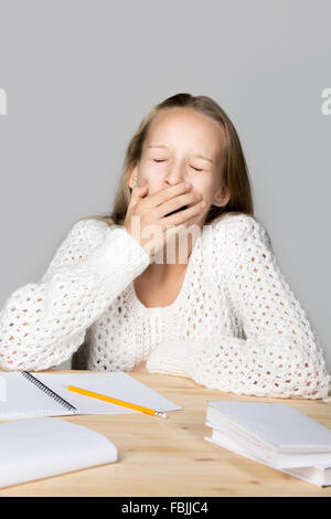 Portrait of sleepy funny beautiful casual girl, sitting at desk, yawning with closed eyes, tired or bored with hard school task Stock Photo