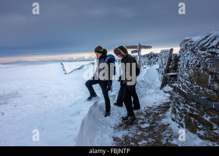 Pen-y-ghent in winter with three walkers leaving the summit wall, Yorkshire Dales. Stock Photo