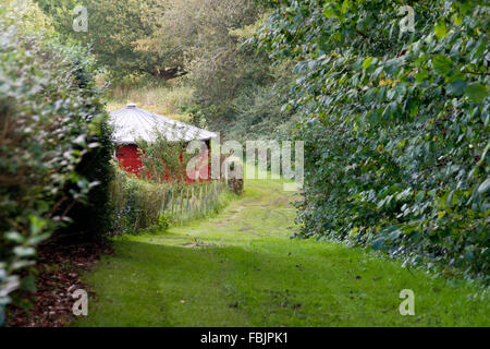 Round building with red walls alongside a country path through lush countryside in Grasten, Denmark. Stock Photo