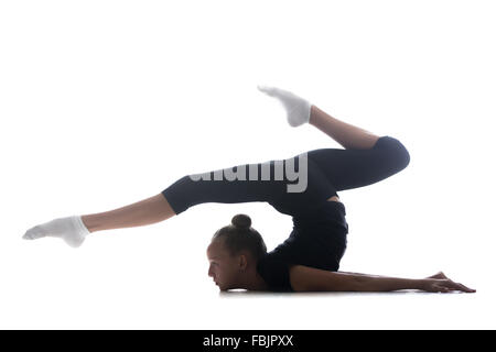 Beautiful cool young fit gymnast athlete woman in sportswear doing art gymnastics, backbend acrobatic exercise, full length Stock Photo