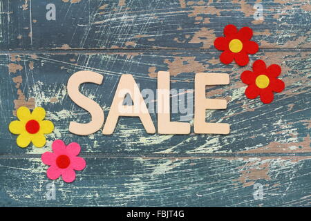 Word sale written with wooden letters on rustic surface and colorful flowers Stock Photo
