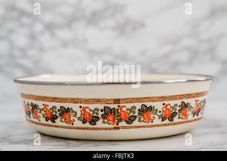 Yellow vintage enamel plate with flower design on white marble background with copy space Stock Photo