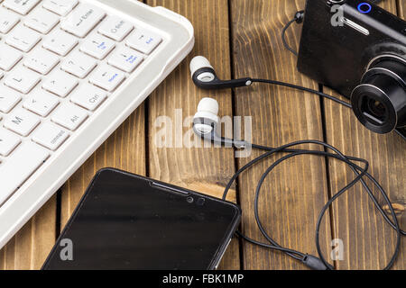 Laptop, smart phone, photo camera and headset on wooden background. Stock Photo