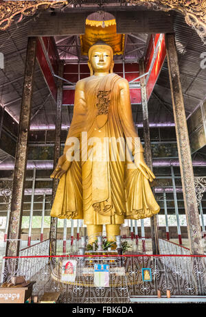 Typical standing golden Buddha statue in a typical holy shrine within Mandalay Hill pagoda temple complex, Mandalay, Myanmar (Burma) Stock Photo