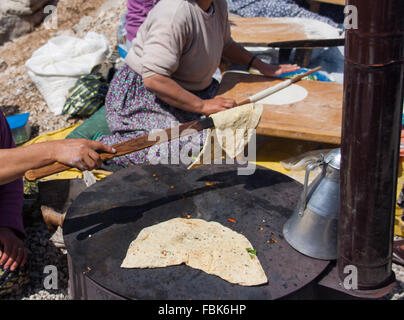 Old turkish women bake Gozleme bread in traditional fire oven Stock Photo