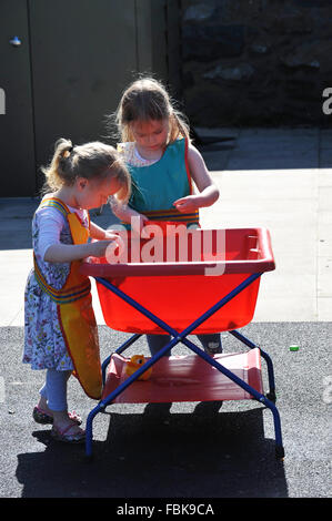 Two little girls playing with water in a nursery Stock Photo