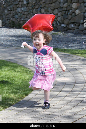 Young girl running and playing with balloon at a nursery Stock Photo
