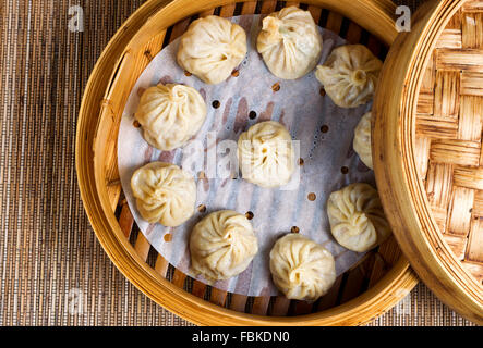 High angled view of cooked dumplings inside of bamboo steamer with lip partially off. Stock Photo